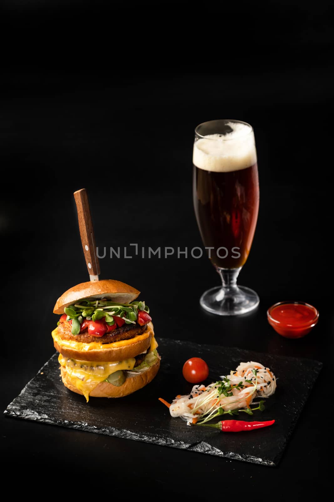 Big delicious burger on the board with a glass of beer by sveter