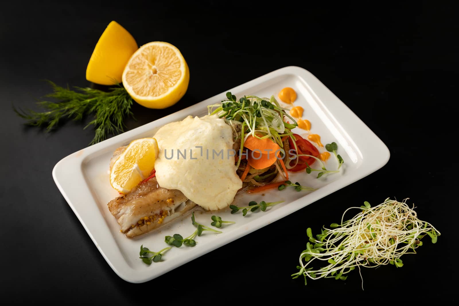 White fish fillet under sauce on a plate against a black background