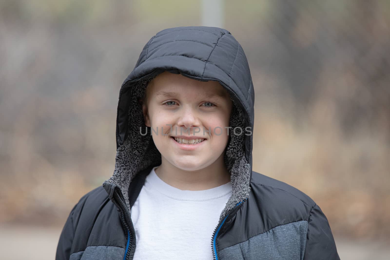 Child smiling while trying to stay warm in cold weather by wearing a coat