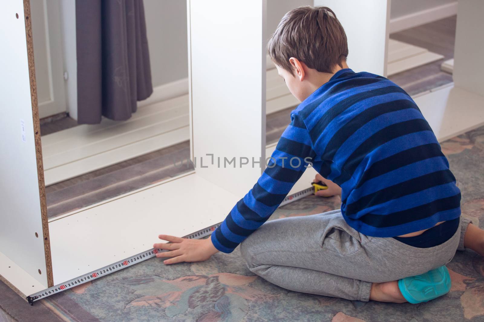 Boy assembling furniture by destillat