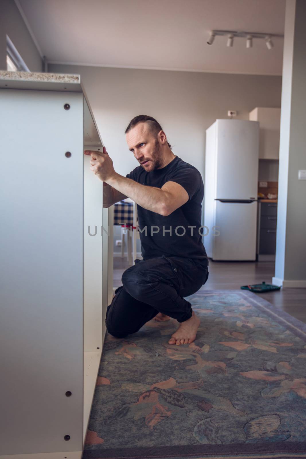 Man assembling furniture by destillat