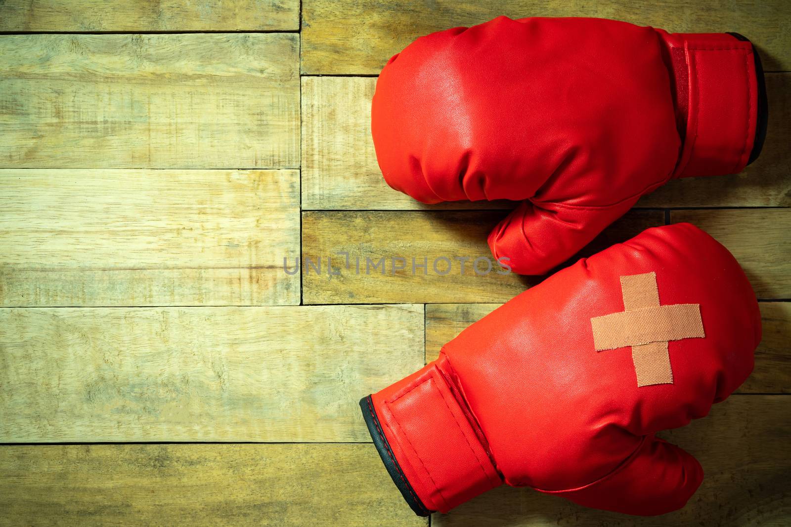 Red boxing gloves placed on wooden floor at the gym. by SaitanSainam