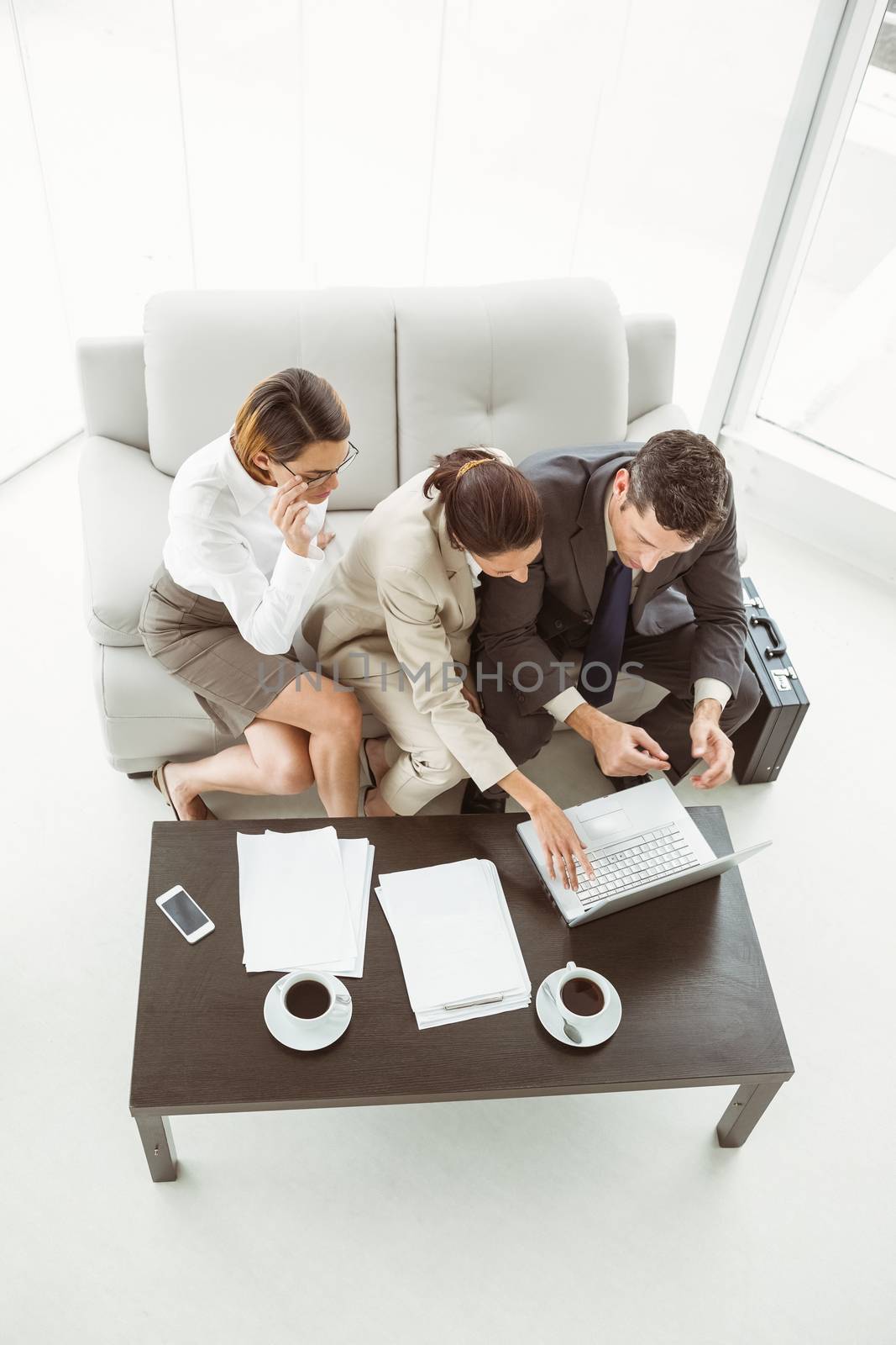 Three young business people using laptop in office