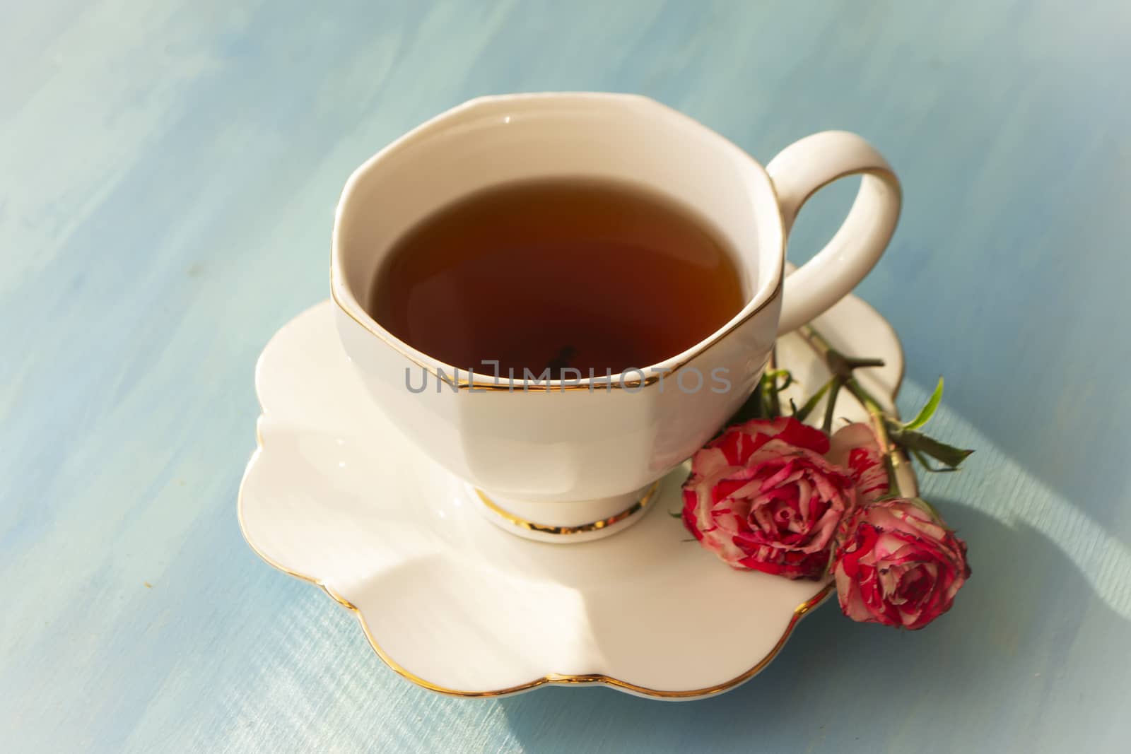 Afternoon tea in white classic with roses on blue wooden background