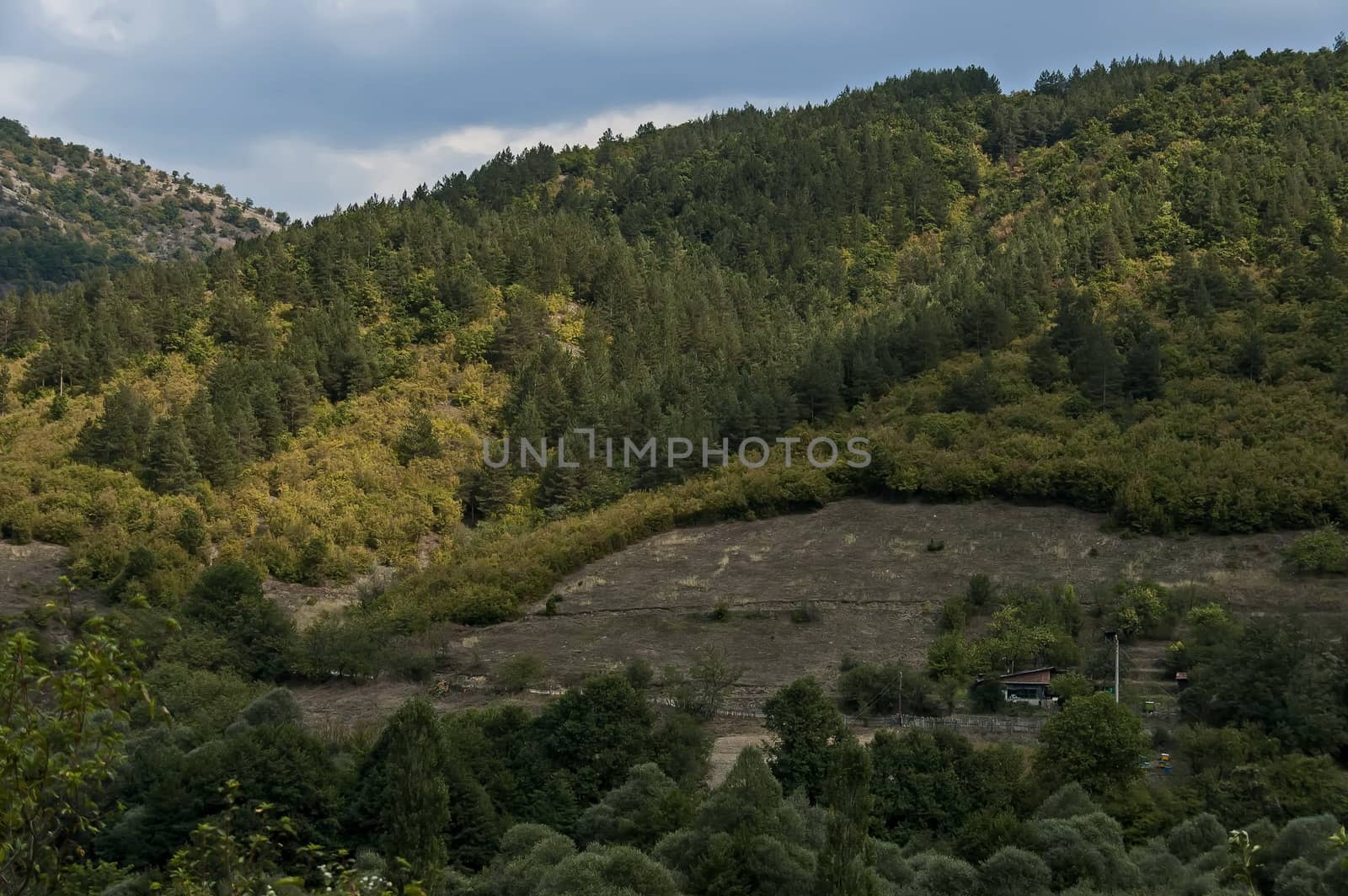 Amazing autumn view of glade, field, peak, deciduous forest, trees and small village in Sredna gora mountain, Bulgaria