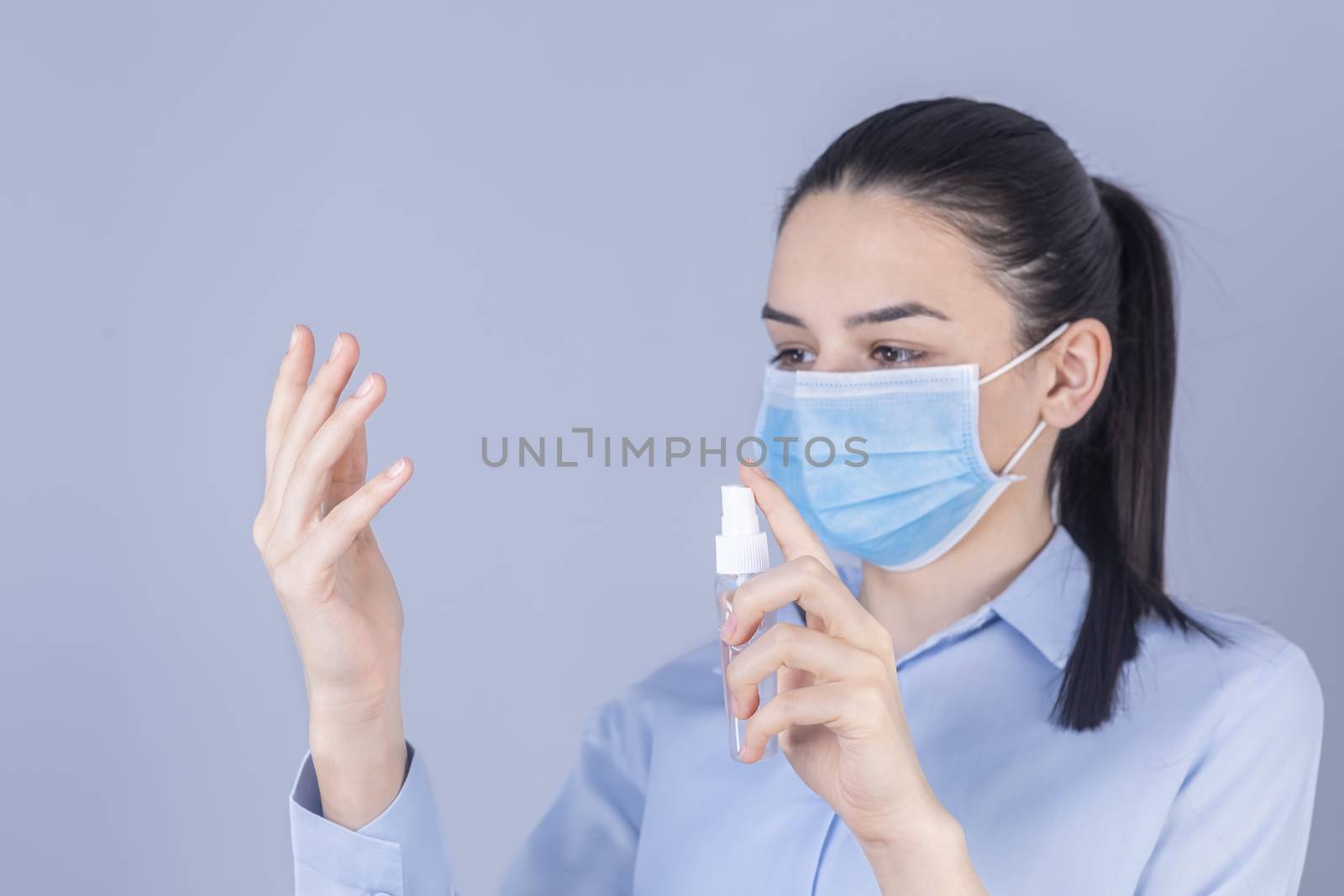 COVID-19 Pandemic Coronavirus. Girl with protective mask holdding alcohol spray cleaning protect disease covid 19. Antiseptic, Hygiene and Healthcare concept. Focus on hand.