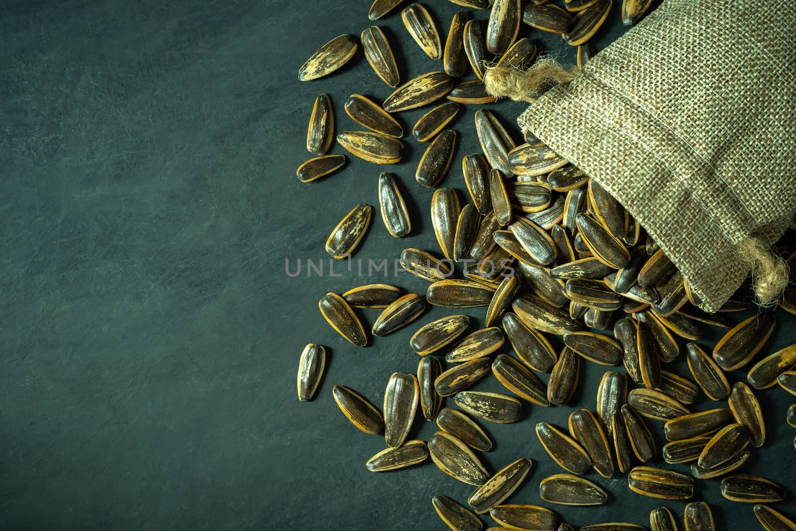 Sun flower seeds in small burlap bag on black cement floor. by SaitanSainam