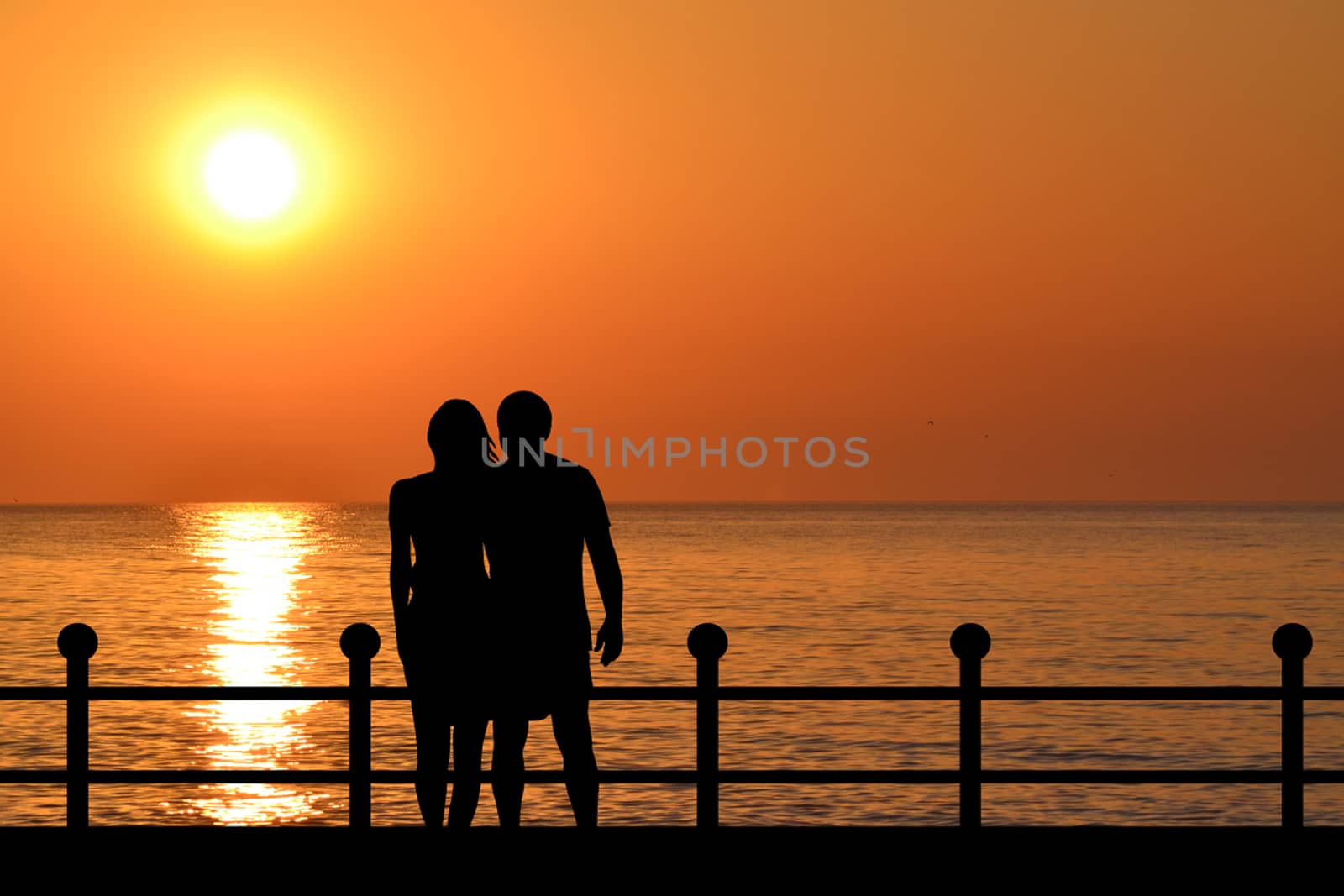 Silhouette of couple on the waterfront at sunrise by hibrida13