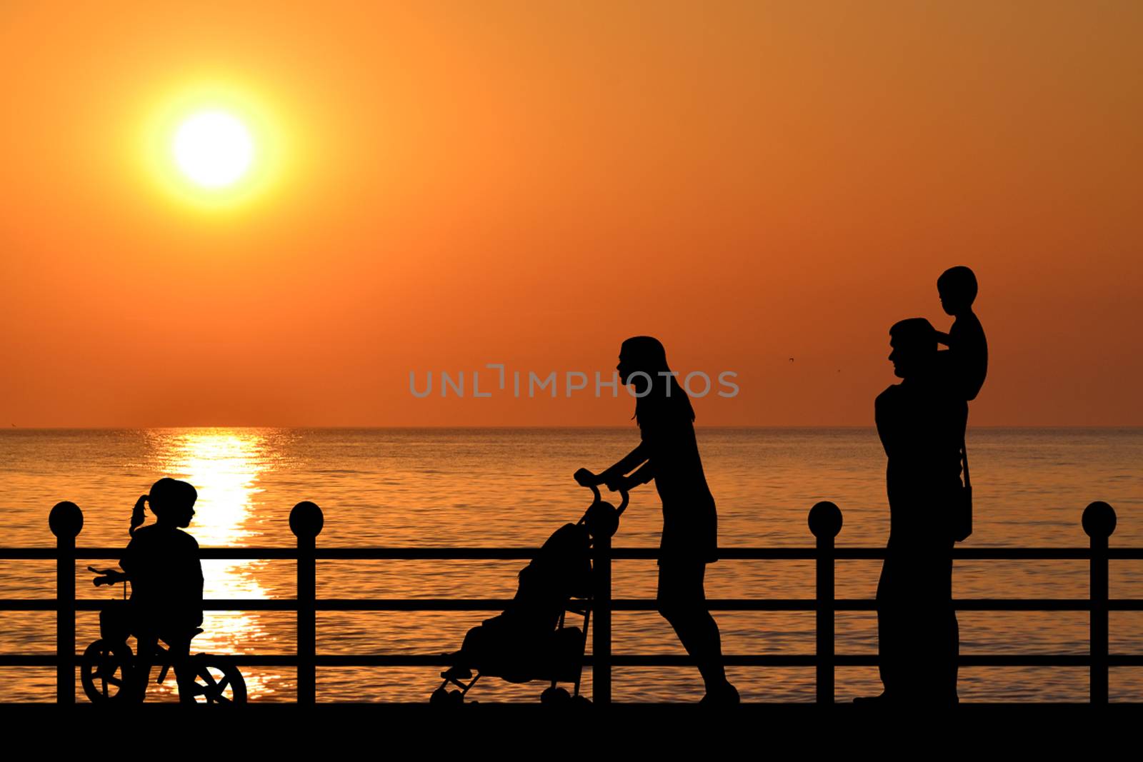 Family on the waterfront promenade at sunset by hibrida13