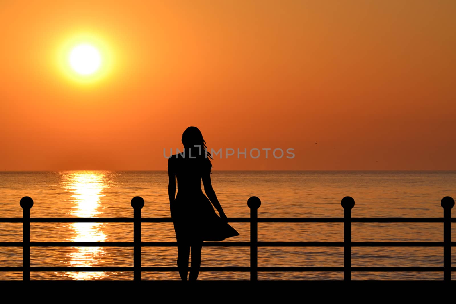 Woman silhouette enjoying sunrise on the waterfront