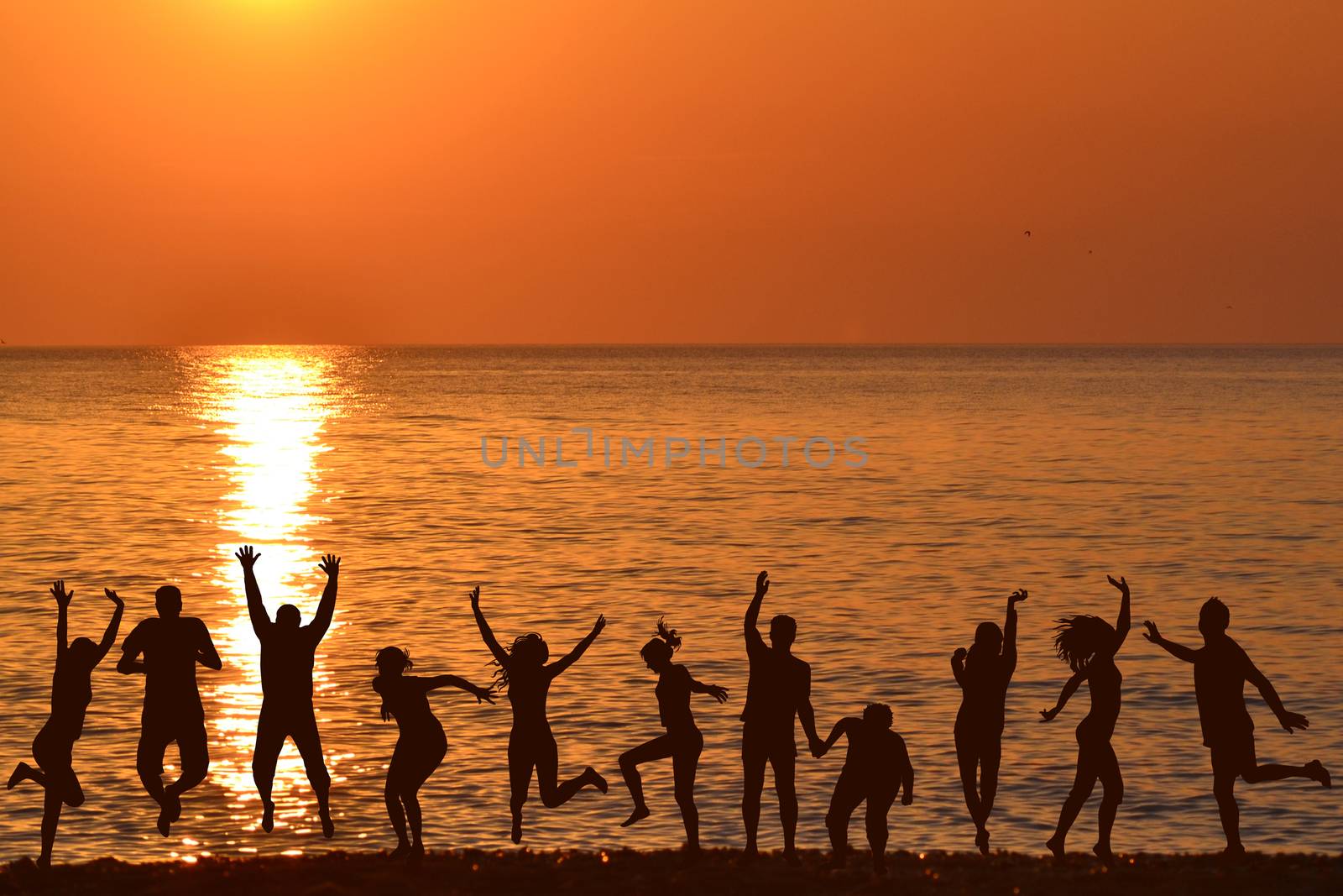 Men and women jumping and enjoying life at sunrise on the beach