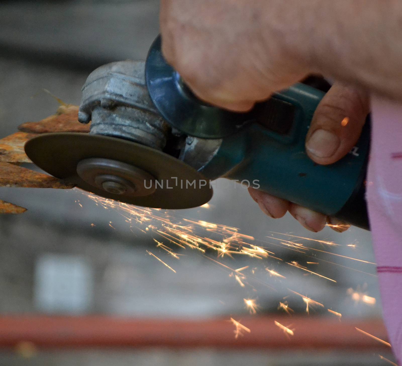 Man working with electric grinder tool on steel pipe and sparks flying