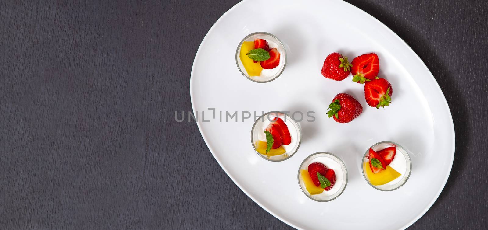 white plate with strawberries and mango. Lifestyle food served in glasses