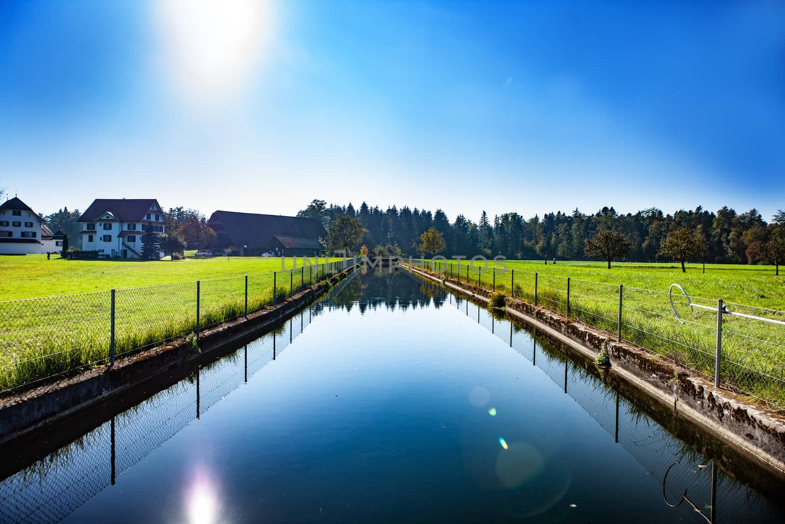 sunshine over a river with green pasture surroundings by PeterHofstetter