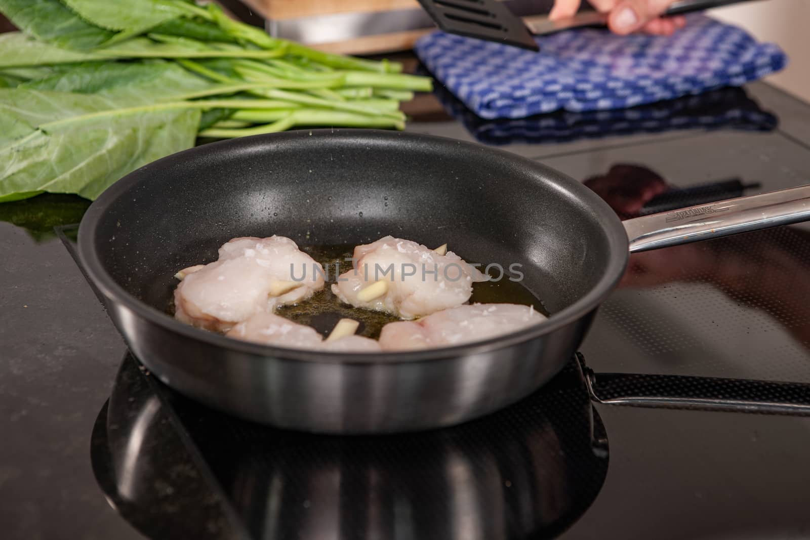 hands of cook preparing food in a frying pan with meat and vegetables by PeterHofstetter