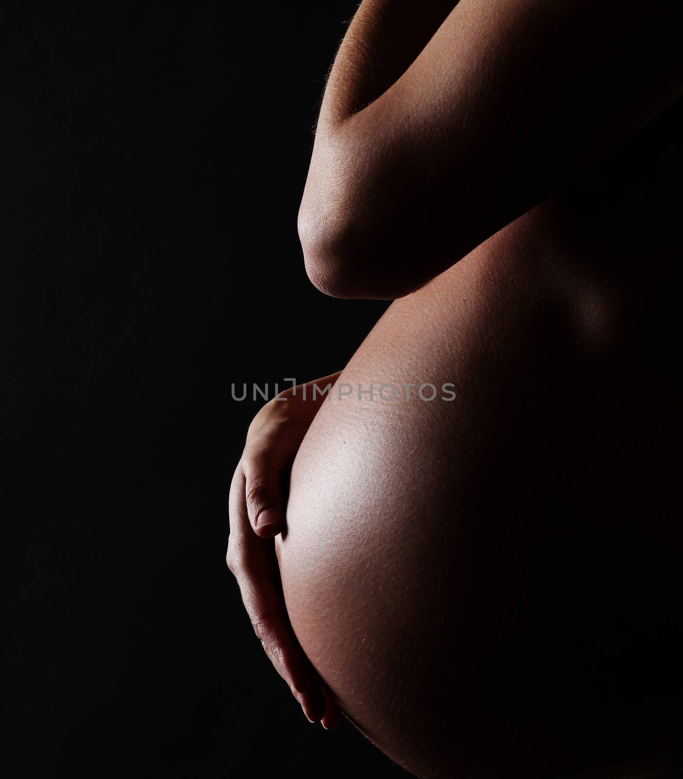 stomach of a pregnant woman on black background with copy space by PeterHofstetter