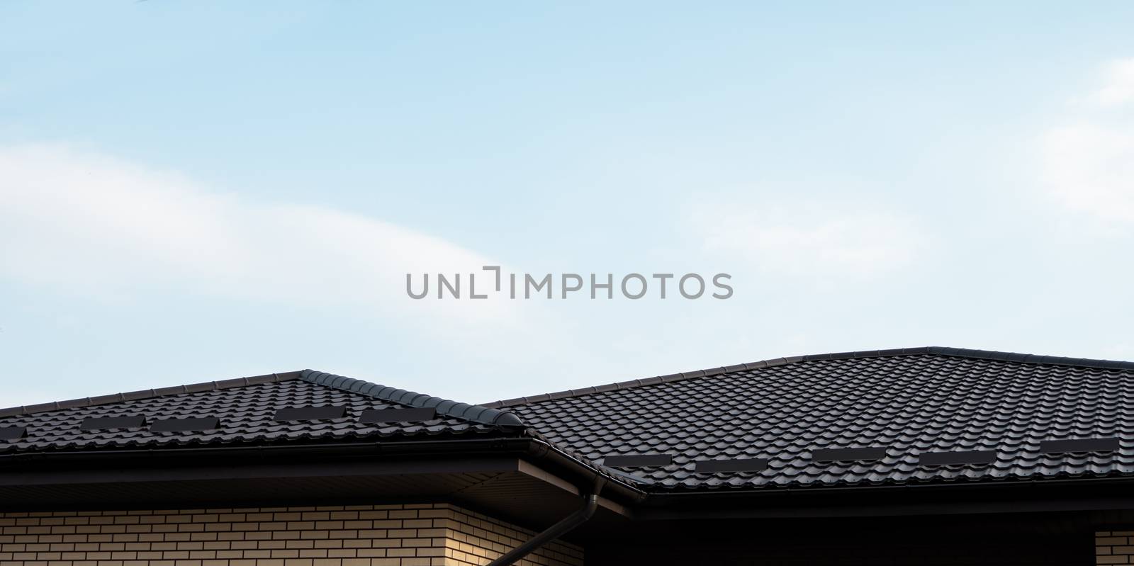 Brown metal tile roof. Roof metal sheets. Modern types of roofing materials. Roof of the house, metal roof tile against the blue sky. Building. by vovsht
