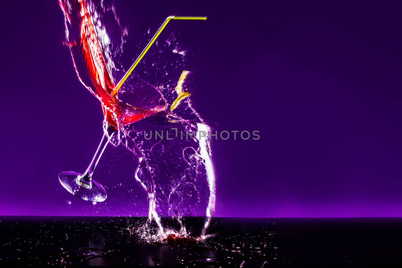 New Years concept of a crashing alcohol glass with purple background