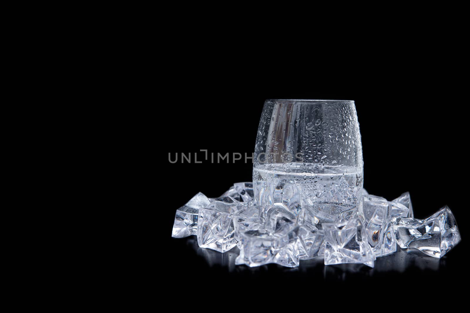 glass of water with ice and bubbles on black background. Shot from side view