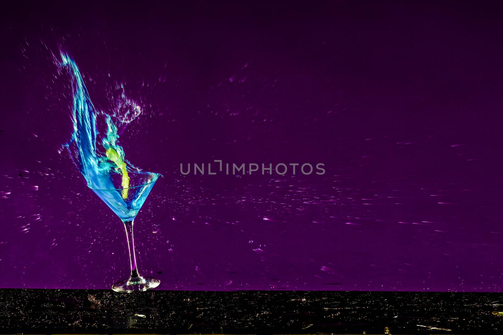 New Years concept of a crashing alcohol glass with purple background by PeterHofstetter