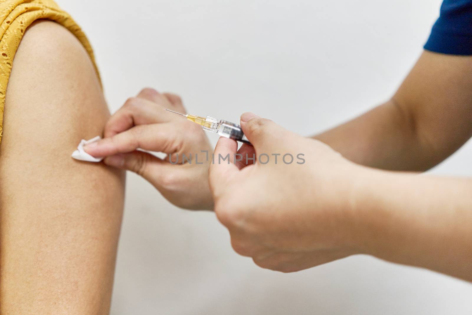 Nurse holding hypodermic syringe and alcohol pad is injecting vaccine by eaglesky