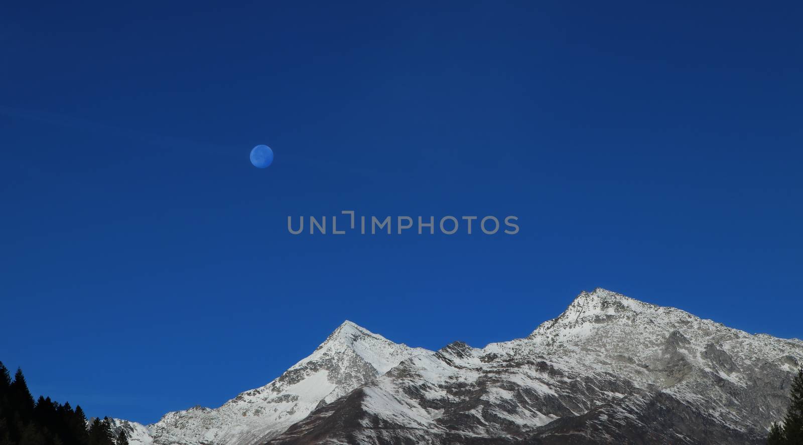 mountains in switzerland with moon shining. snow covered mountain