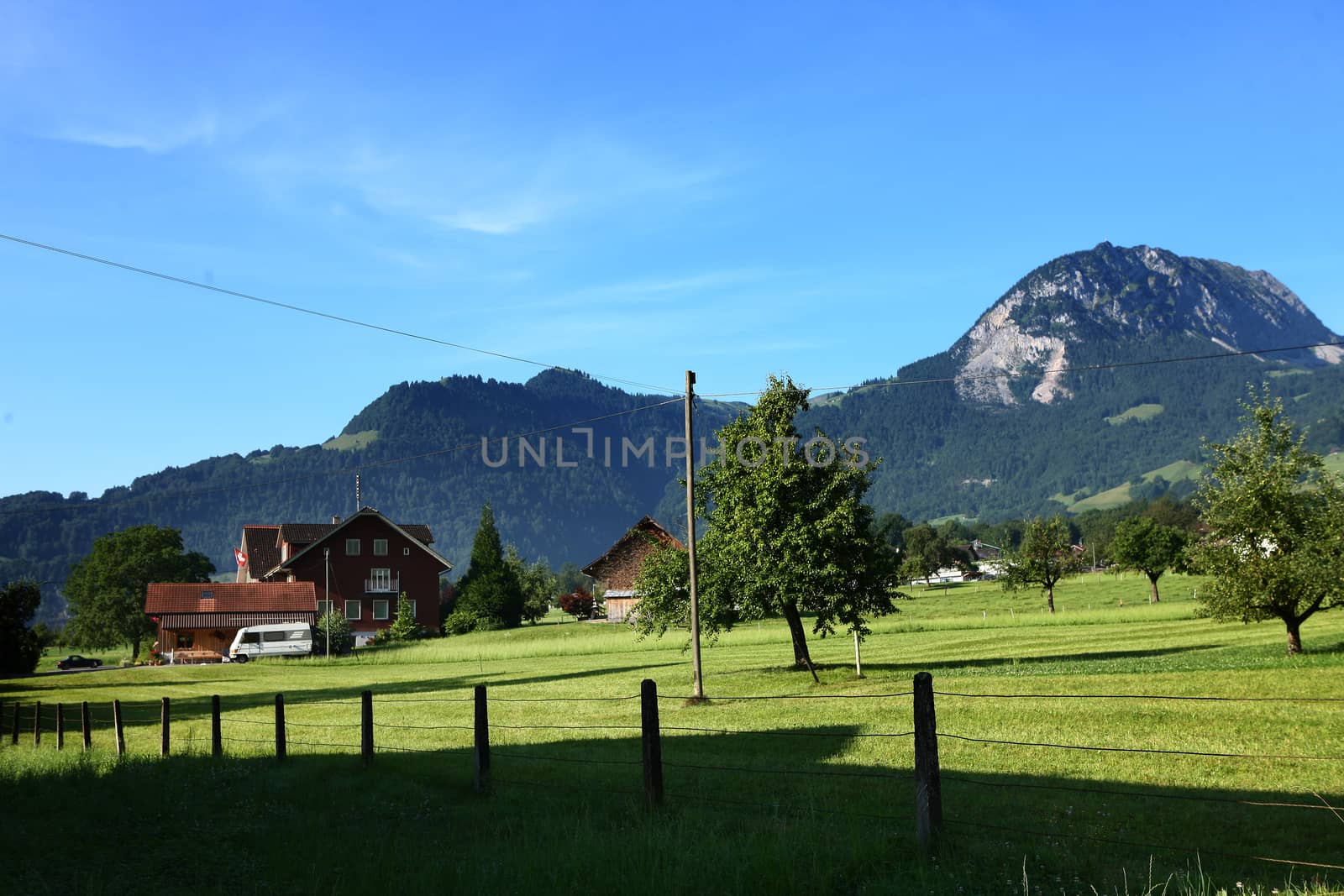 Mountains in switzerland, green grass and swiss house by PeterHofstetter