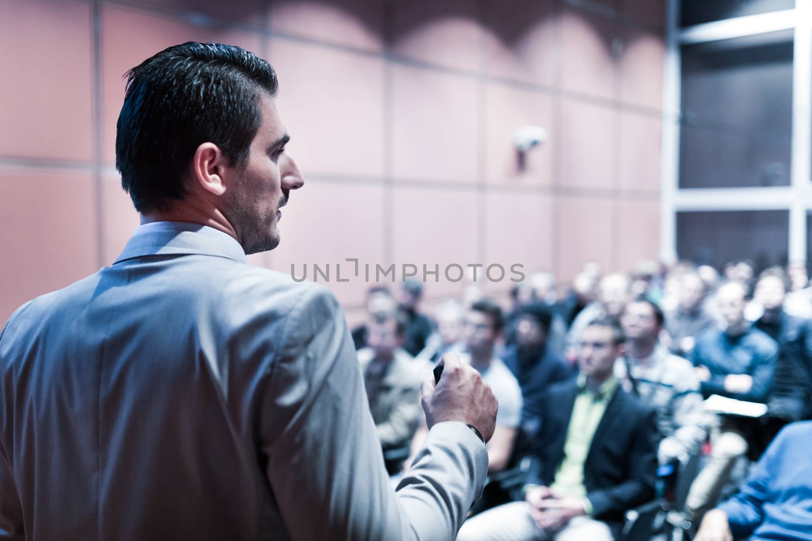 Speaker giving a talk on corporate business conference. Unrecognizable people in audience at conference hall. Business and Entrepreneurship event.