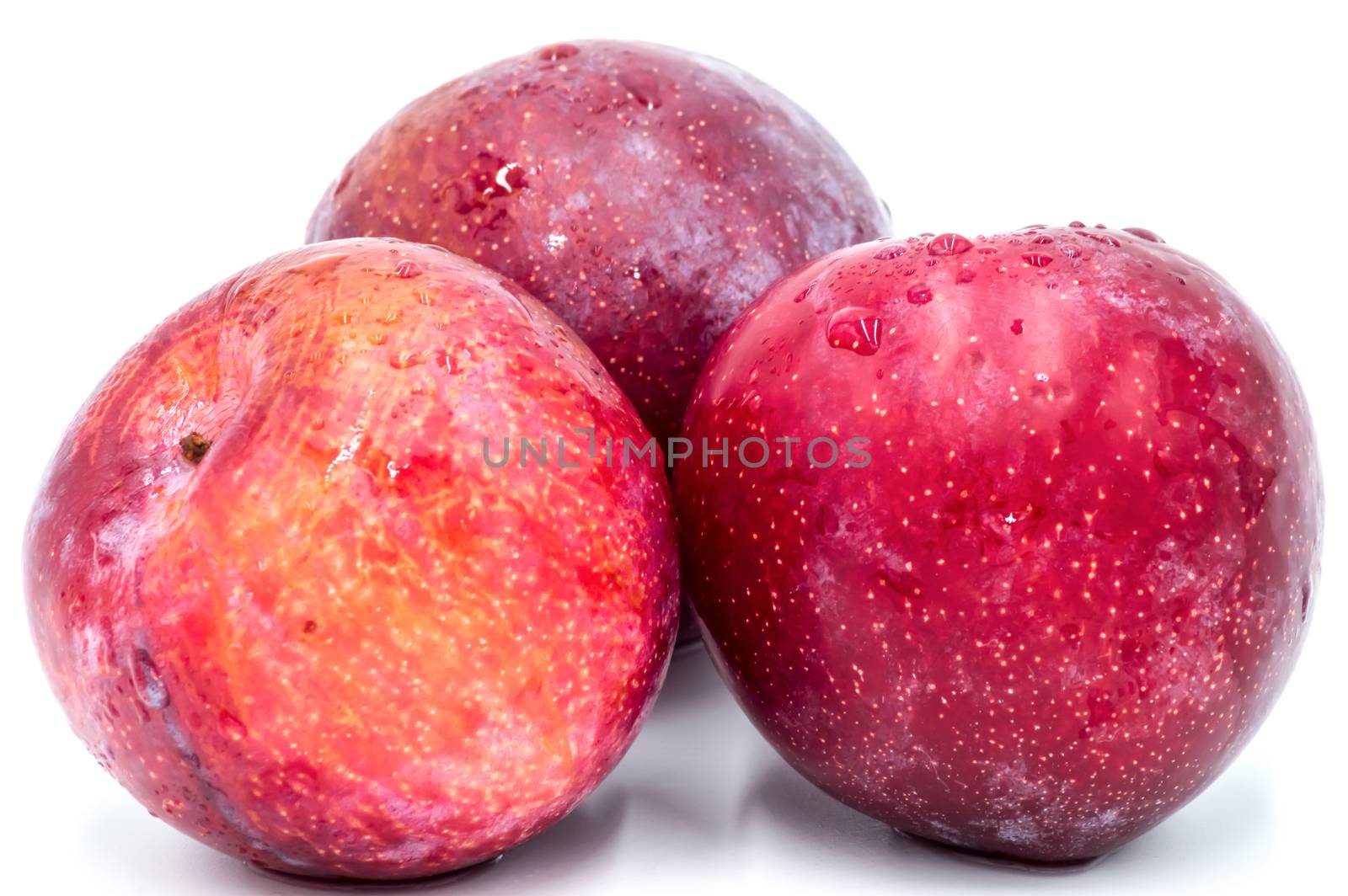 Three ripe red round plums isolated on white. Big plan