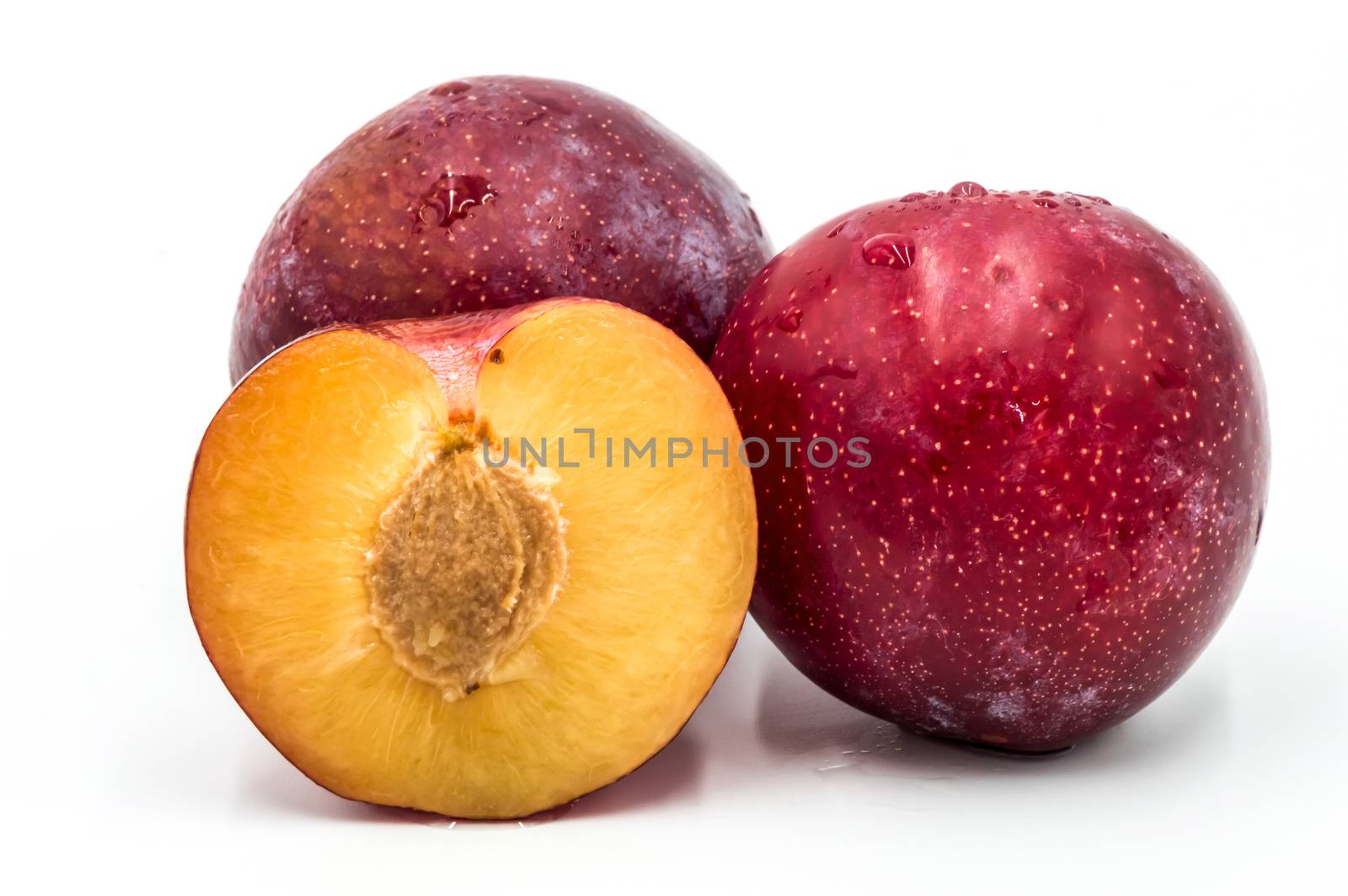 Ripe red round plums and a quarter isolated on white. Big plan
