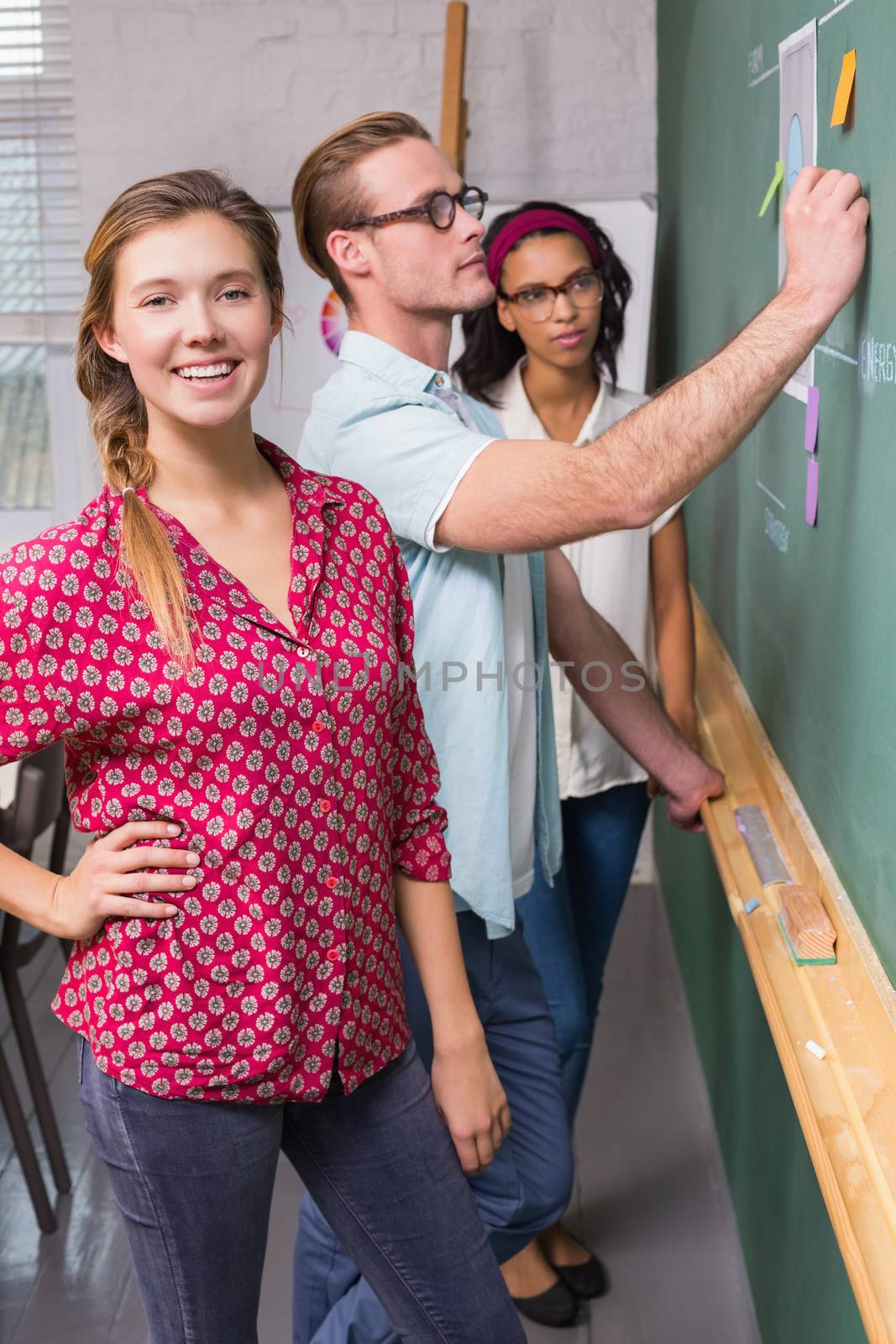 Young creative business people at work by blackboard at office