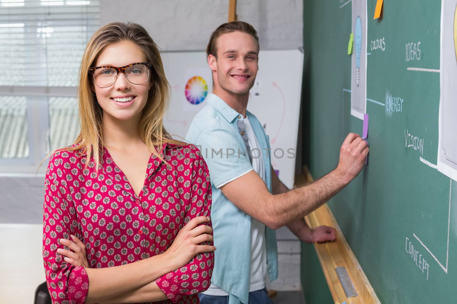 Young creative business people at work by blackboard at office