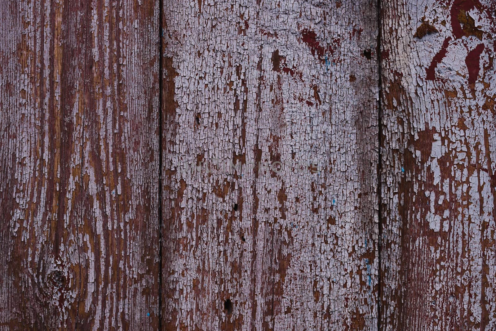 Old red wooden texured door surface closeup. Relief on surface. Stock photo of old wooden door pattern of aged boards with scratches. Red and gray colors on photo.