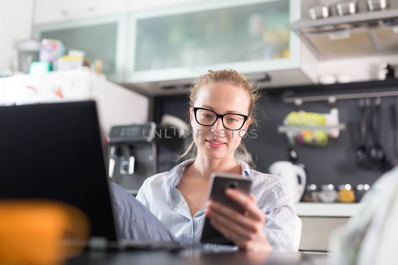 Stay at home and social distancing. Woman in her casual home clothing working remotly from her kitchen dining table in the morning. Video chatting with friend, family or business clients or partners.