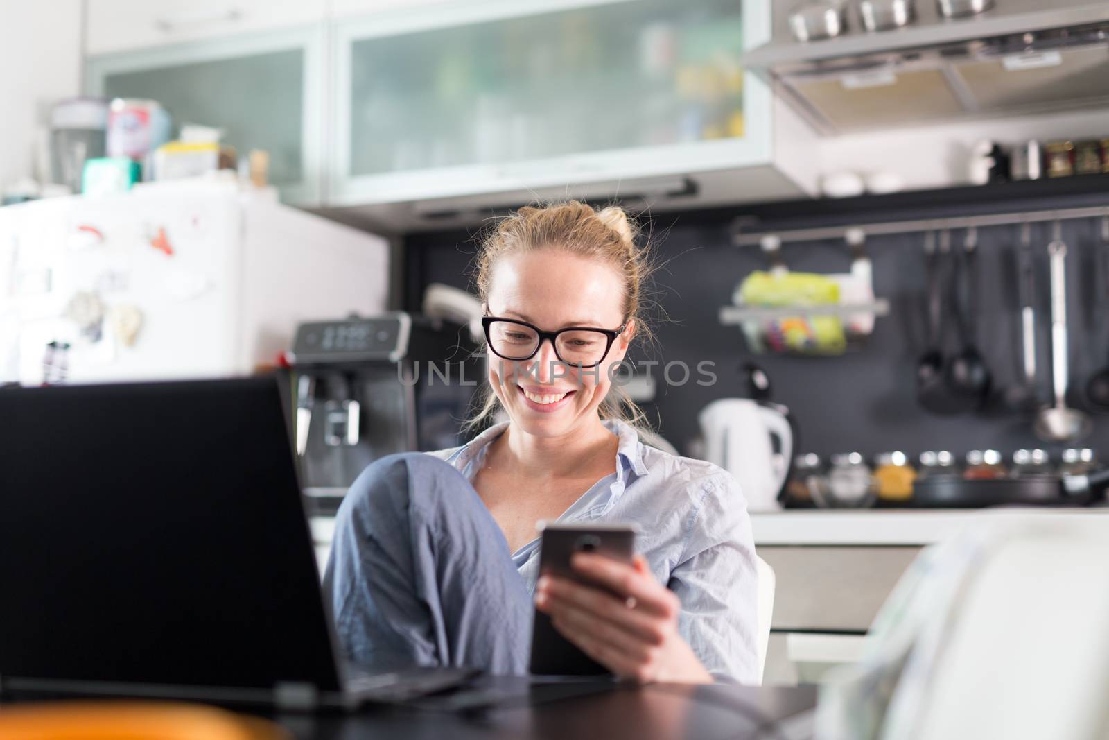 Stay at home and social distancing. Woman in her casual home clothing working remotly from her kitchen dining table in the morning. Video chatting with friend, family or business clients or partners.