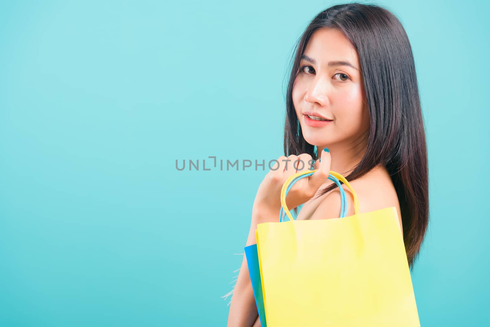 Portrait asian beautiful woman happy smiling her holding shopping bags on blue background, with copy space for text