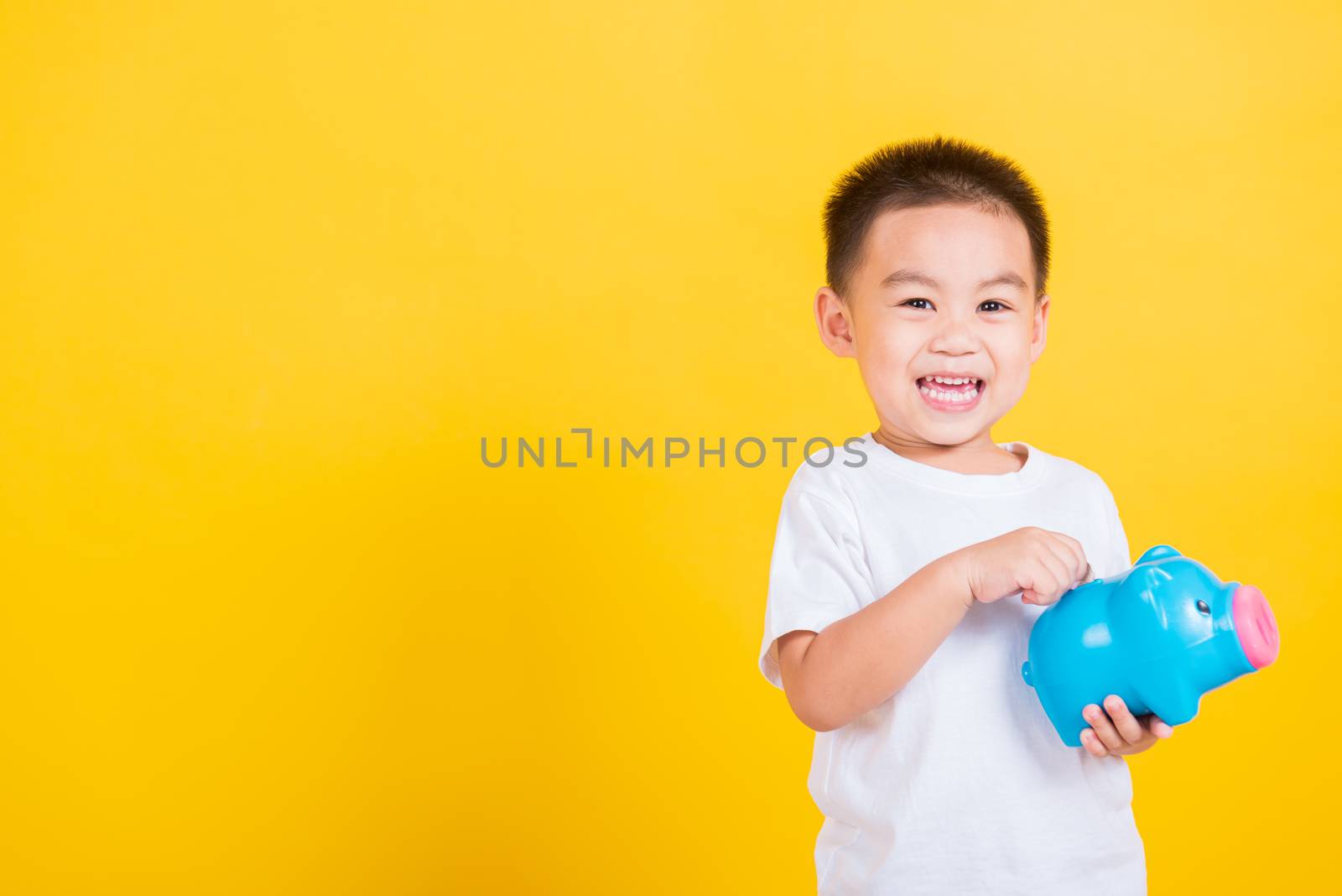 little cheerful child boy smile holding piggy bank by Sorapop
