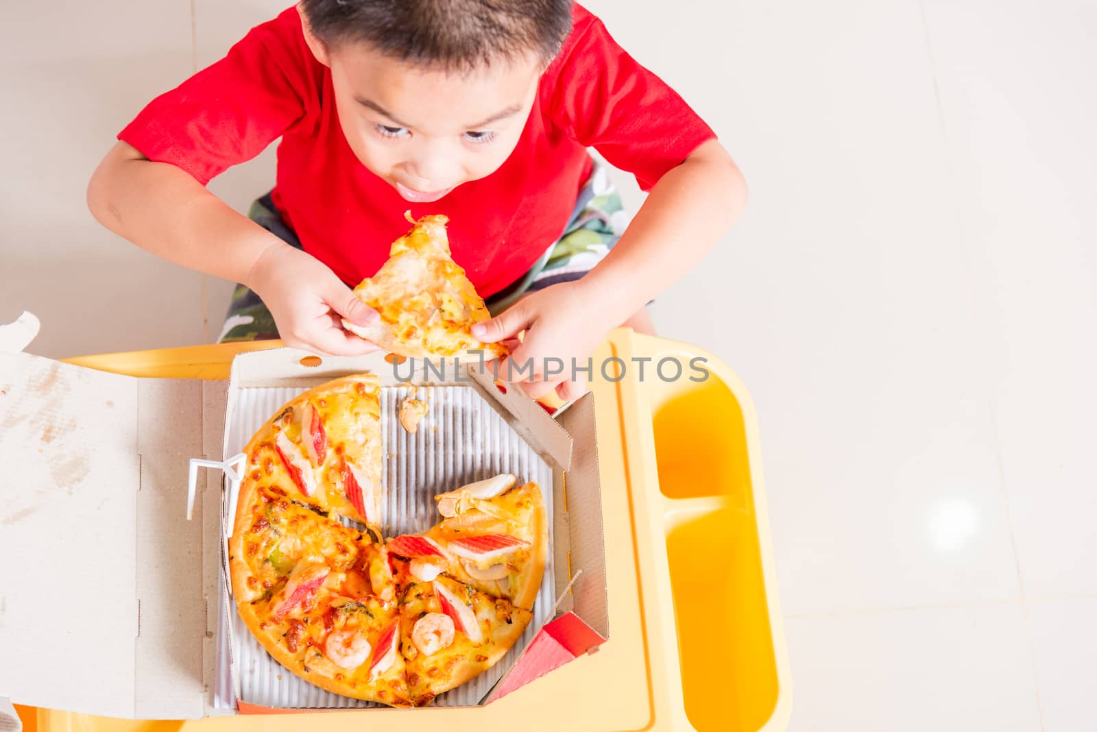 Top view of Cute Little Child eating Delivery Pizza by Sorapop