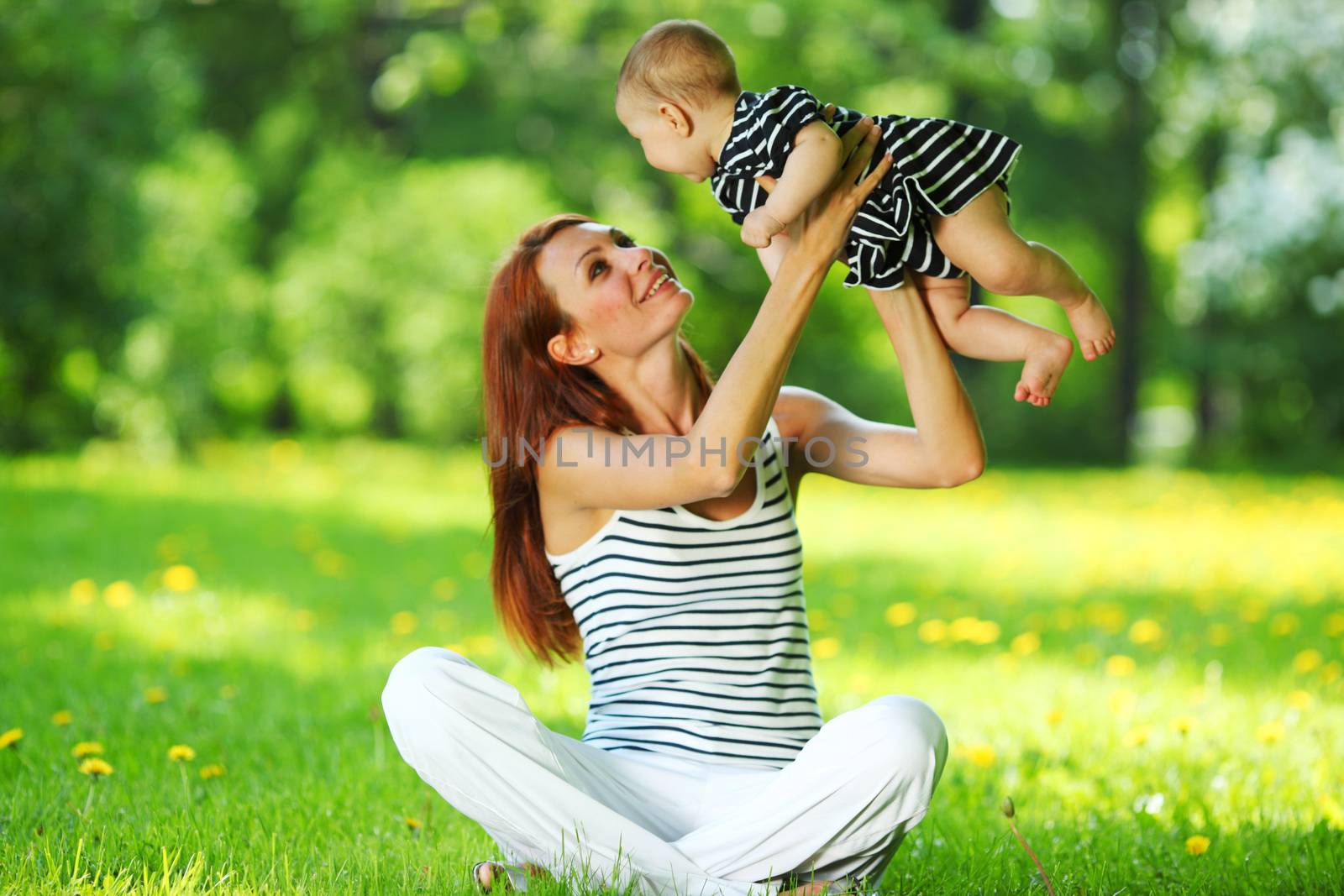 Happy mother and daughter on the green grass in summer park