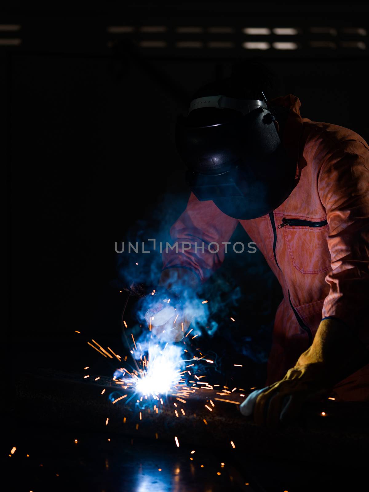 Metal industry workers are welding steel sheets for real estate projects received. Sparkler on dark background, close-up. Heavy work in factory.