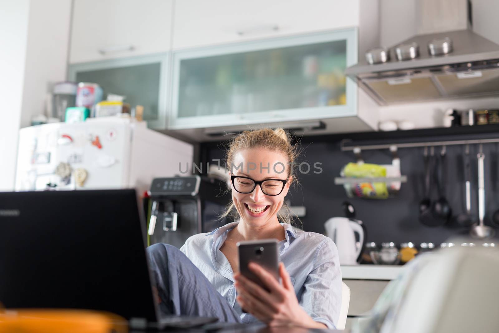 Stay at home and social distancing. Woman in her casual home clothing working remotly from kitchen dining table. Video chatting using social media with friend, family, business clients or partners.