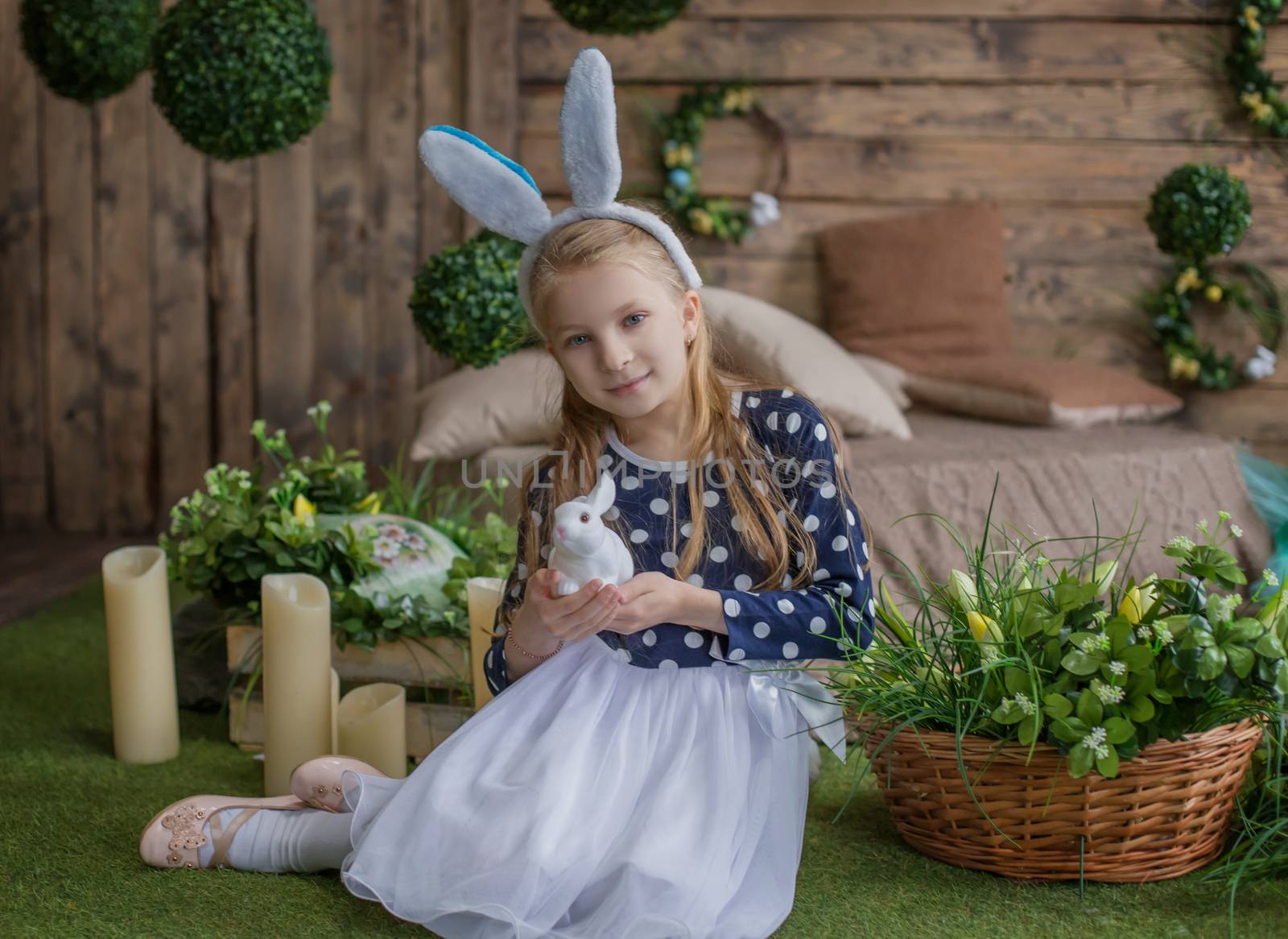 Funny portrait of girl having fun on Easter wearing bunny ears and holding eggs on eyes during spring season