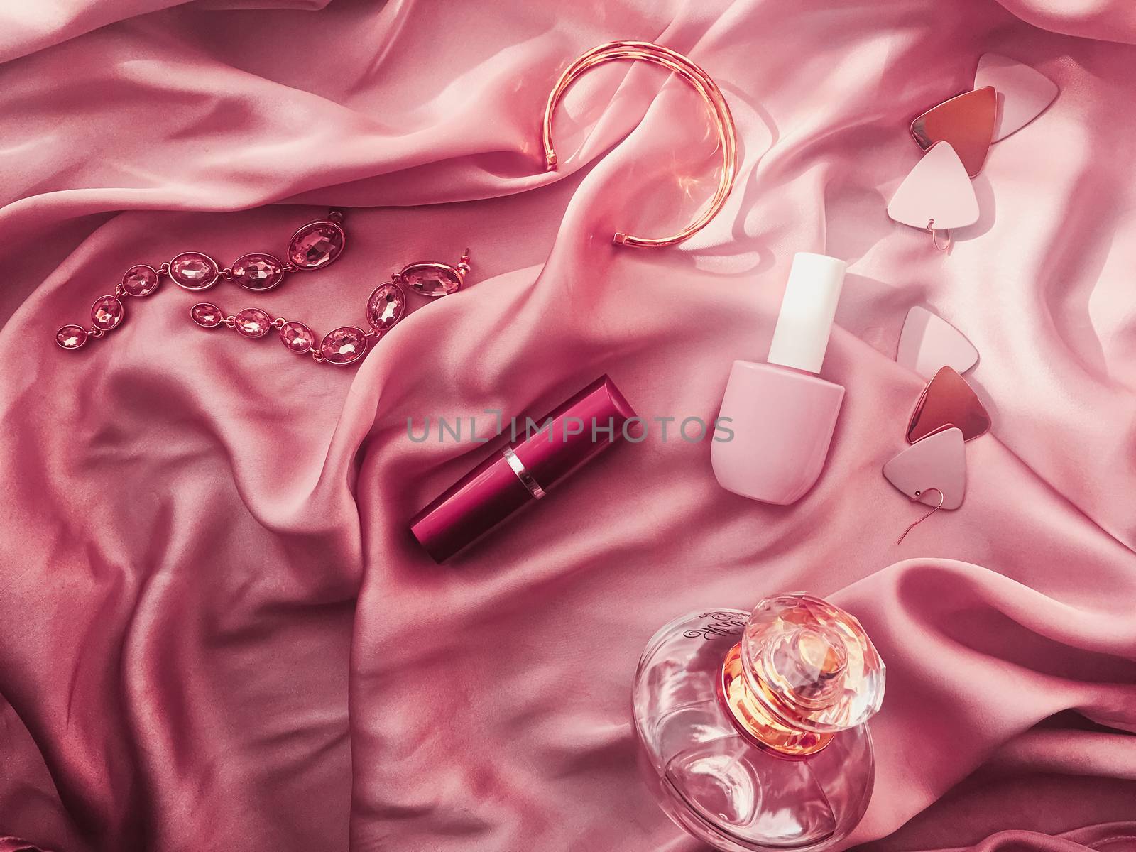 Fashionable and stylish accessories, jewelry and make-up products on pink silk background, beauty and fashion concept