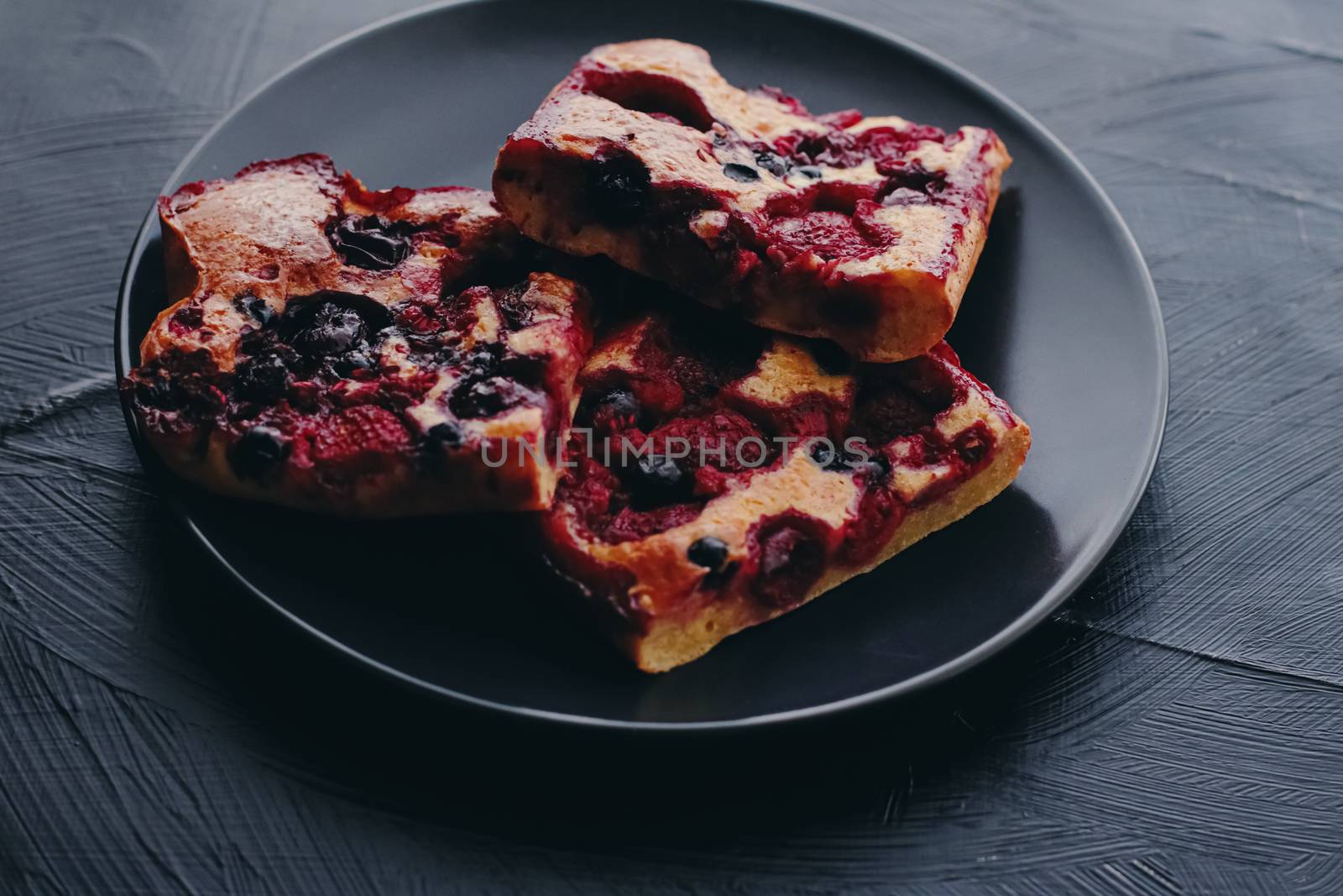 Berry pie on black plate, rustic homemade food with organic ingredients on black background