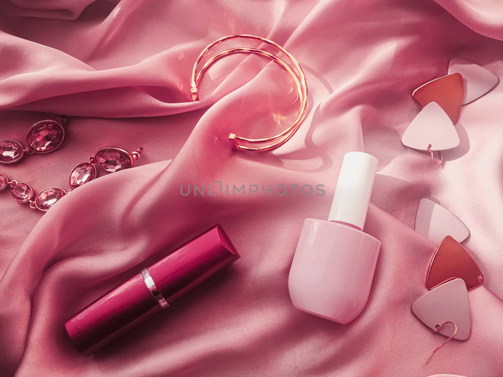 Fashionable and stylish accessories, jewelry and make-up products on pink silk background, beauty and fashion concept