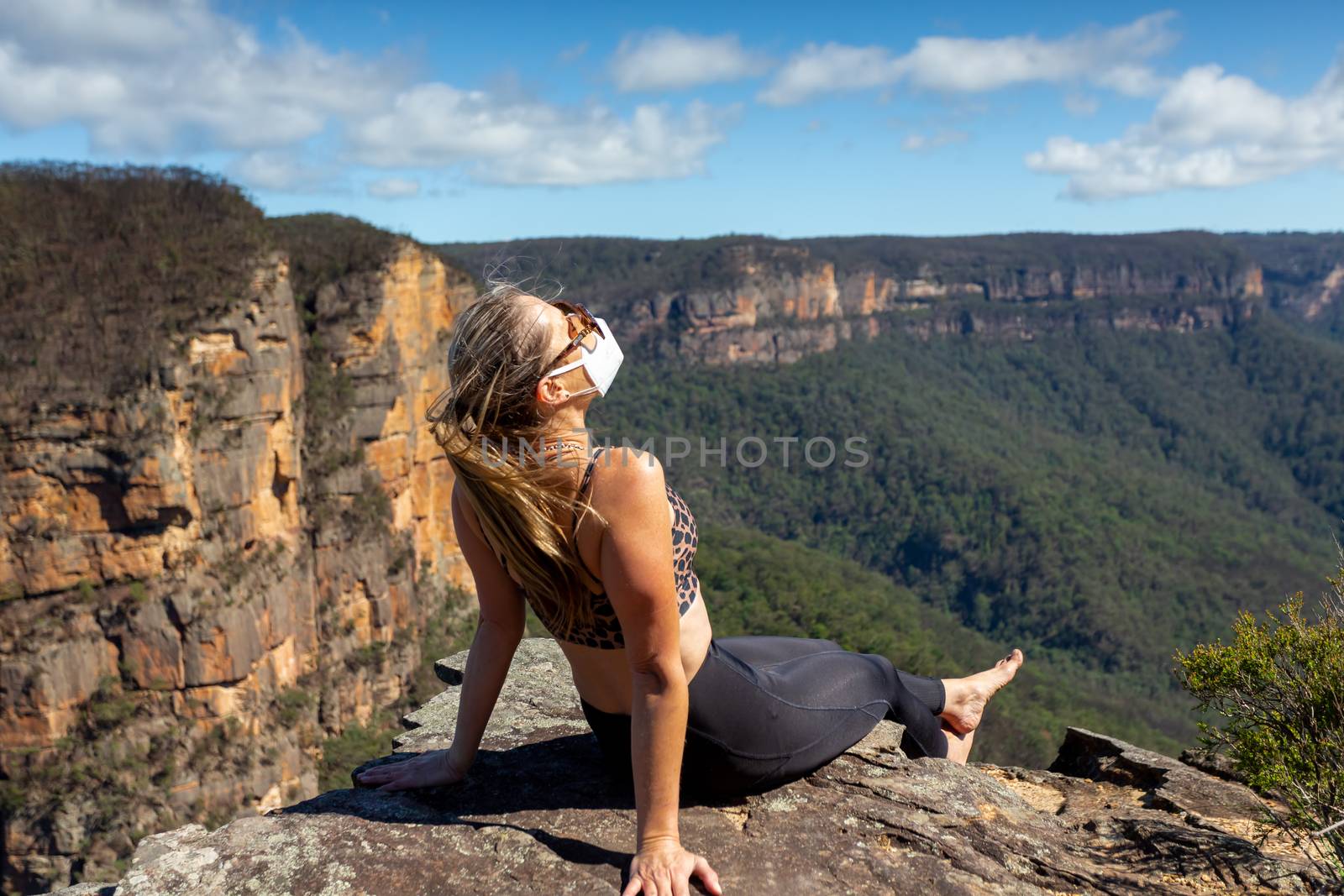 Hiker takes a break on a cliff overlooking valley during the coronavirus COVID-19  pandemic.  Mental health  and exervise is necessary during lockdown