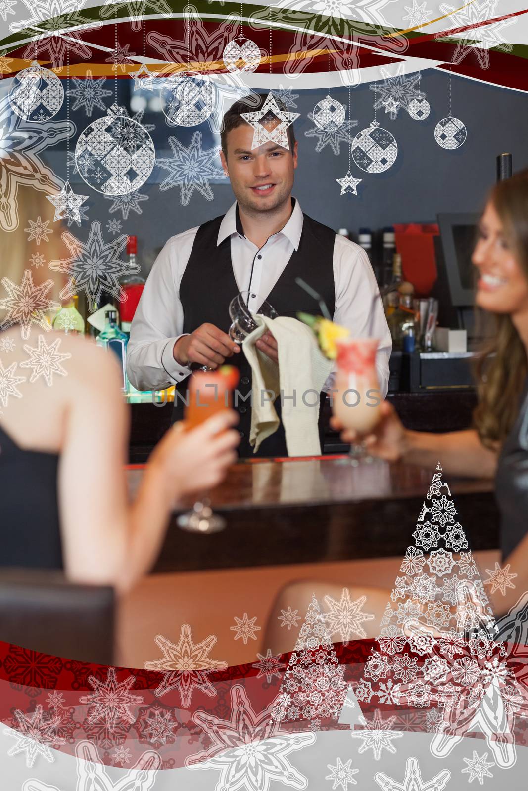 Handsome bartender working while gorgeous friends talking against christmas frame