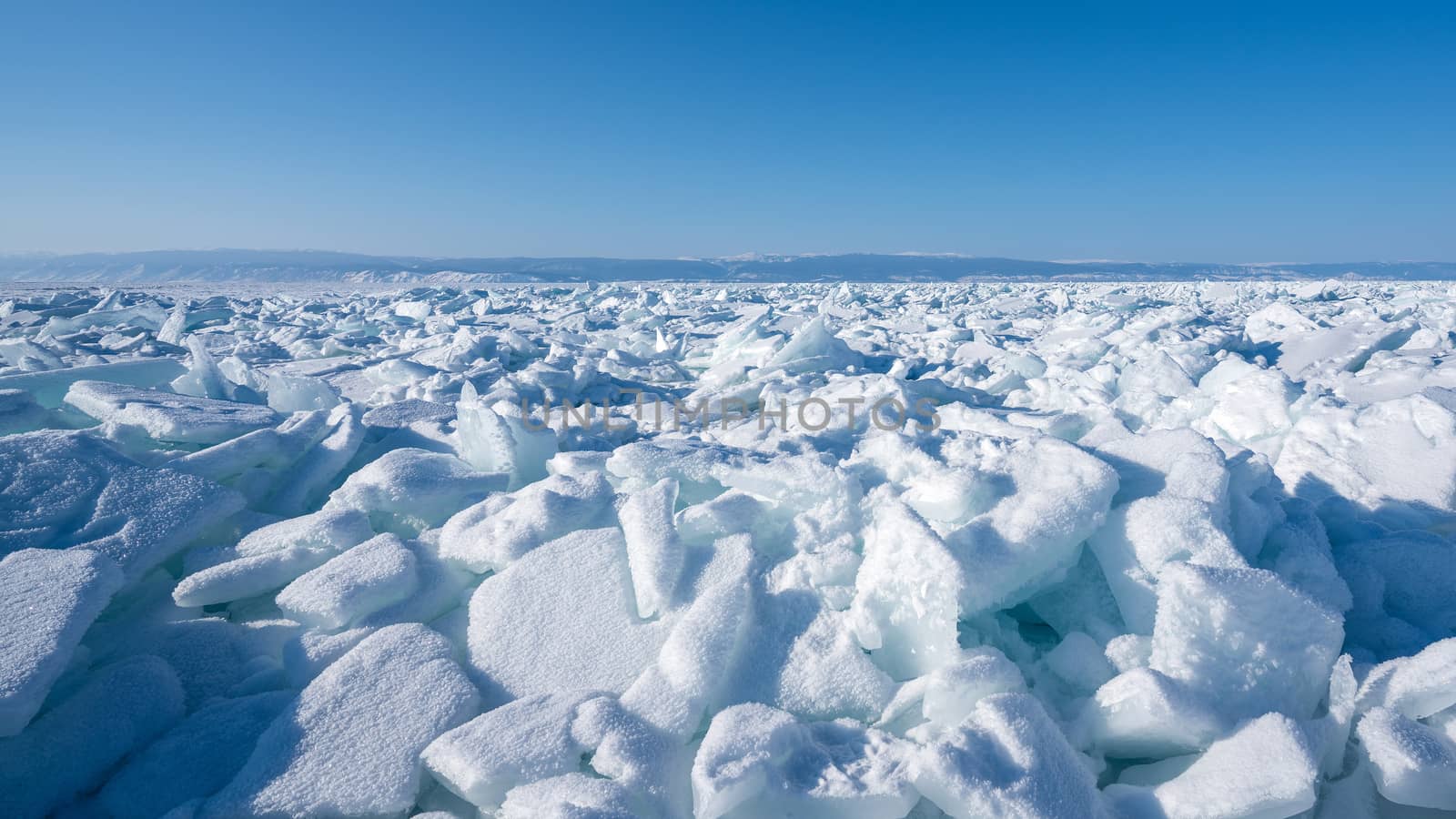 Winter landscape of the frozen Baikal Lake. Fields of ice hummocks with heaps of large blocks of ice. Nature Background.