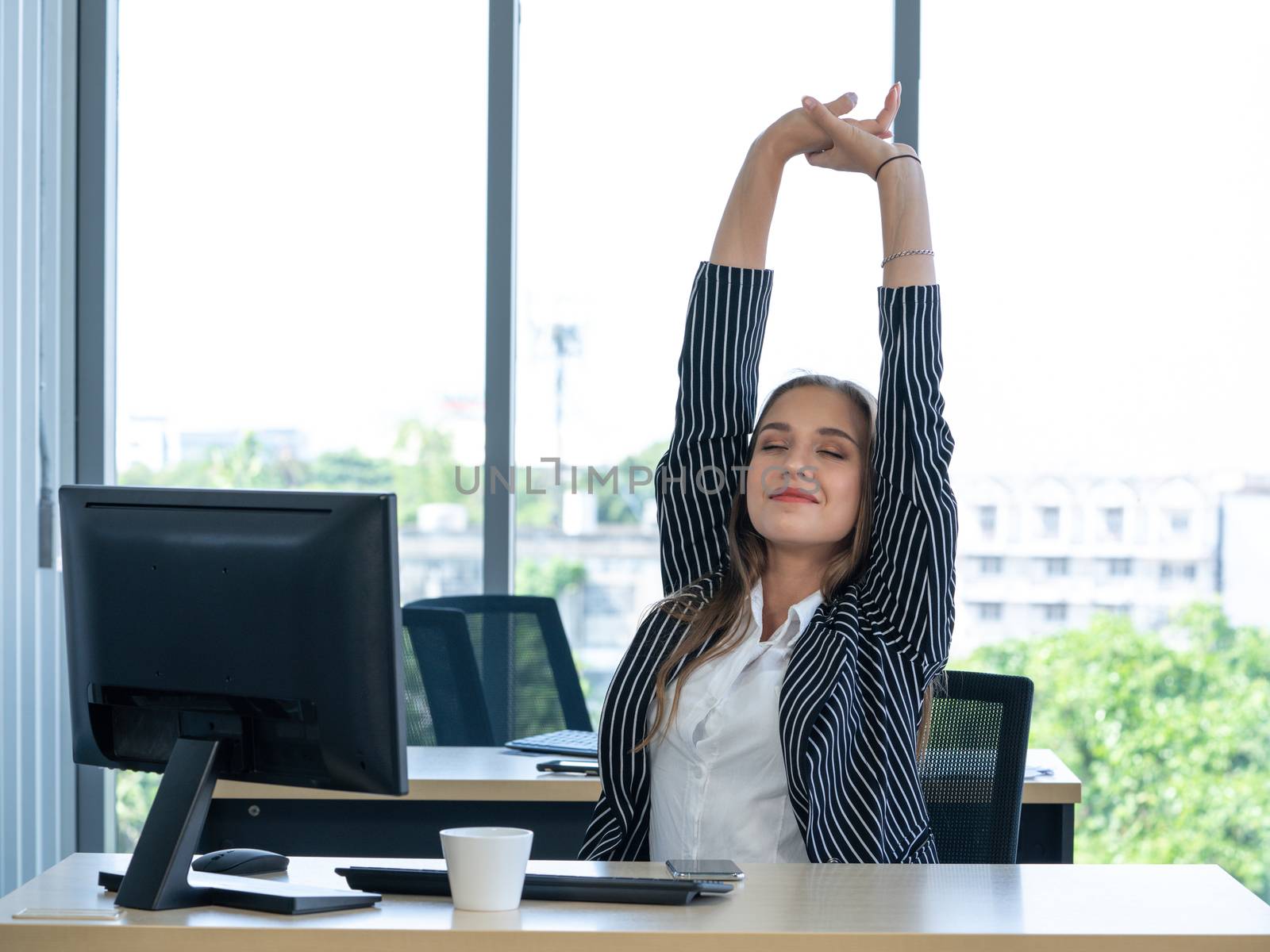 Morning work atmosphere In a modern office. Teenager employees are relaxed and stretching her arms. After clearing the remaining pending work.