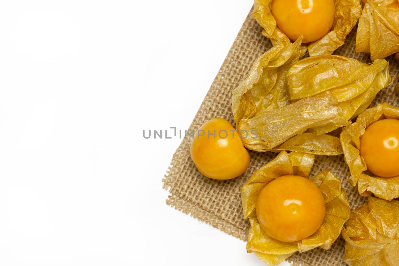 Cape gooseberry on burlap fabric in white background. by SaitanSainam